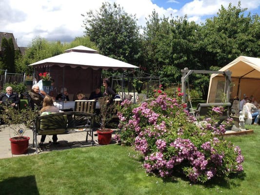 Seniors socializing in a garden with flowers and shaded areas