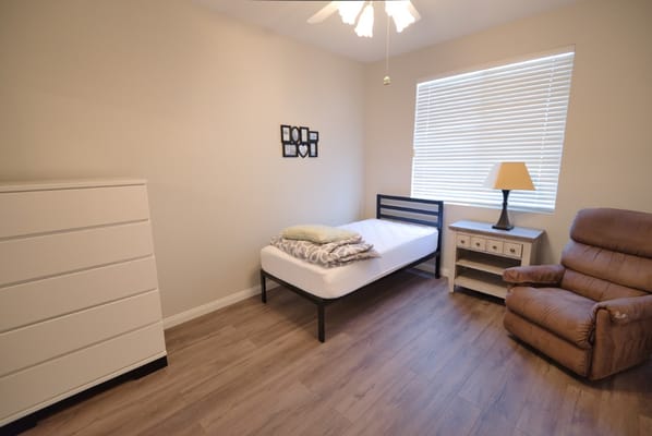 Simple bedroom with a bed, dresser, and armchair