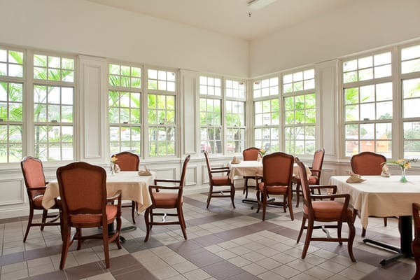 Bright dining room with tables and chairs bathed in natural light from large windows