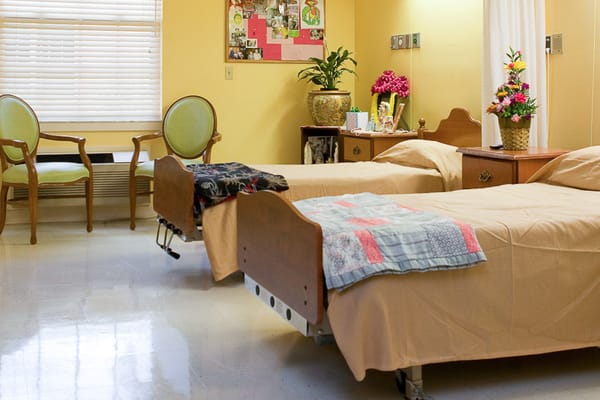 A spacious bedroom with two beds, chairs, and decorative plants.