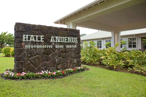 Stone sign for Hale Anuenue Restorative Care Center surrounded by greenery
