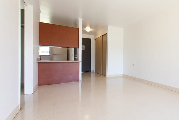 Interior view of a bright, empty room with kitchenette