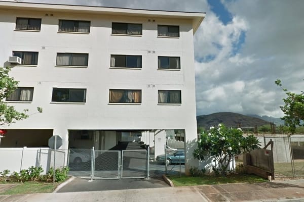 Exterior of a four-story senior living facility with trees and parking area