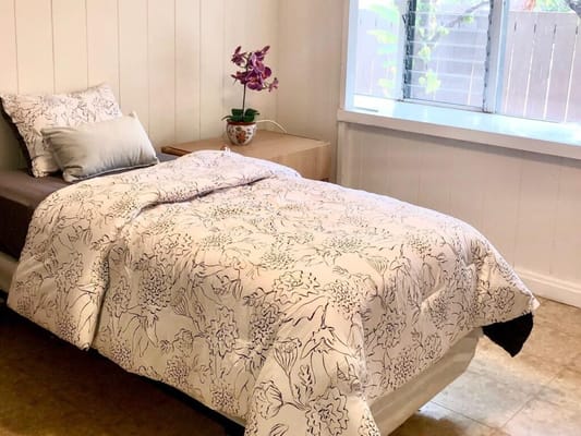 Cozy private room with floral bedding and a plant