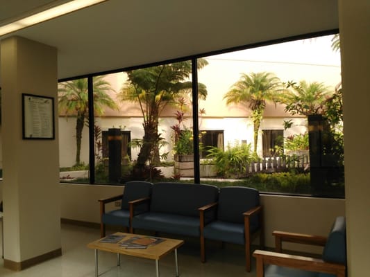 A view of the lobby seating area looking out towards a tropical garden through large windows.