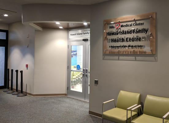 Entrance to Hawaii Island Family Health Center with a sign and seating area