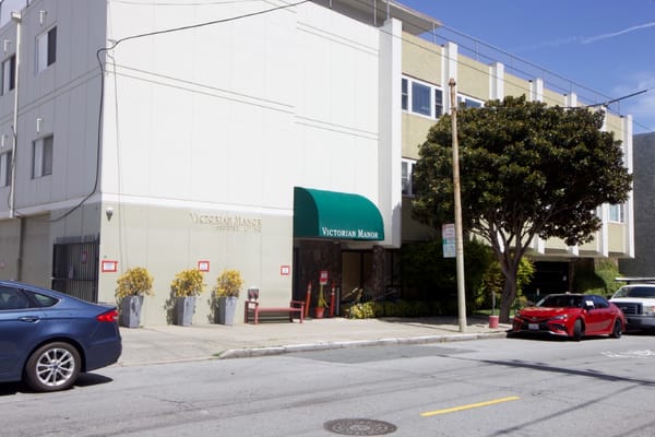 Exterior view of Victorian Manor with entrance and signage