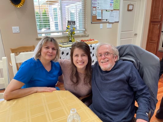 A resident with two staff members enjoying a celebration