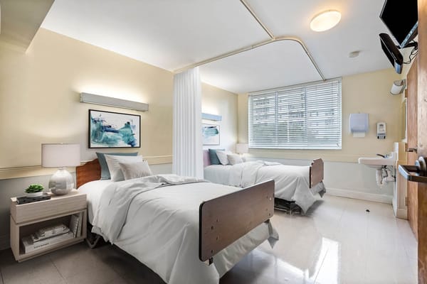 Shared bedroom with two beds, bedside tables, and natural light