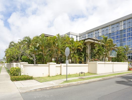 The exterior of Kaluanui Senior Apartments with palm trees and a clear sky.