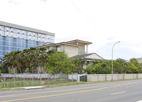 Exterior view of Kaluanui Senior Apartments with palm trees and a modern building.