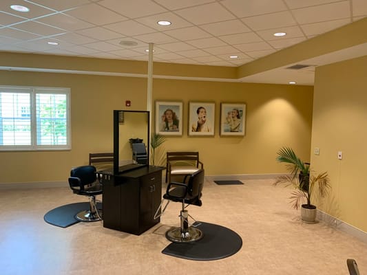Hair salon area with styling chairs and wall art
