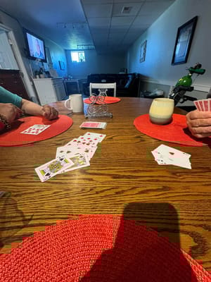 Close-up view of hands playing cards at a table with red placemats