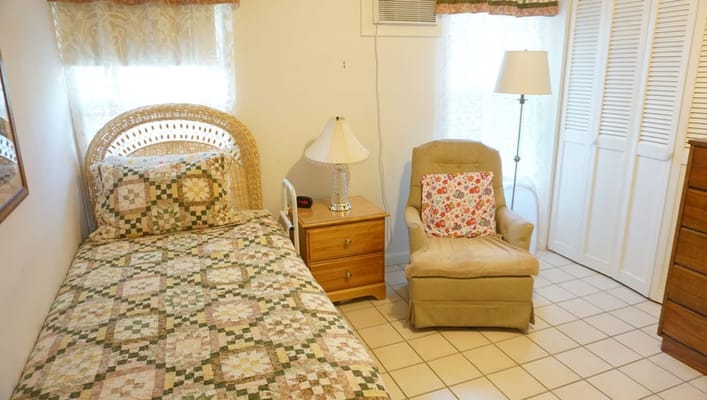A cozy bedroom with a bed, lamp, and armchair