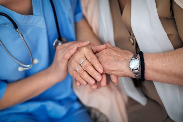 A caregiver holding the hand of a senior resident.