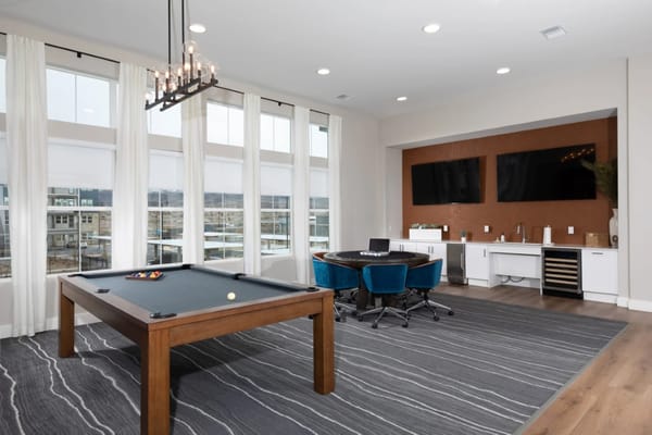 Billiard table and seating area in a bright game room.
