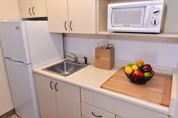 A well-equipped kitchenette with fruits and a microwave