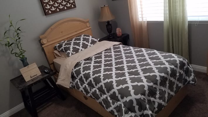 A neatly made bed in a cozy bedroom with natural light.