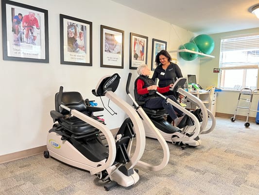 A staff member assisting a resident with exercise equipment