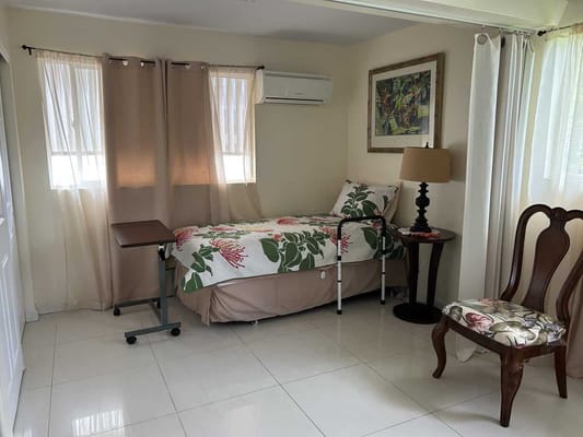 Bright and airy bedroom with a bed, chair, and bedside table.