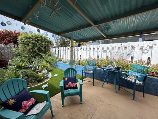 Cozy outdoor lounge with teal chairs and green landscaping at Pualei Care Home.