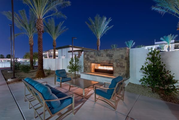 Outdoor seating area with fireplace surrounded by palm trees