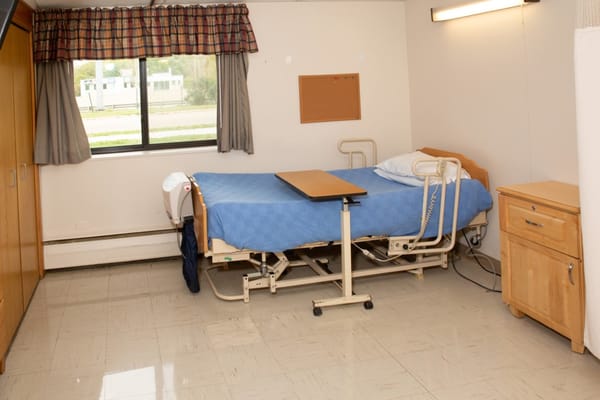 A hospital room with a bed, table, and window