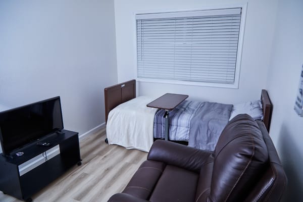 A private bedroom with a bed, a TV, and a seating area.