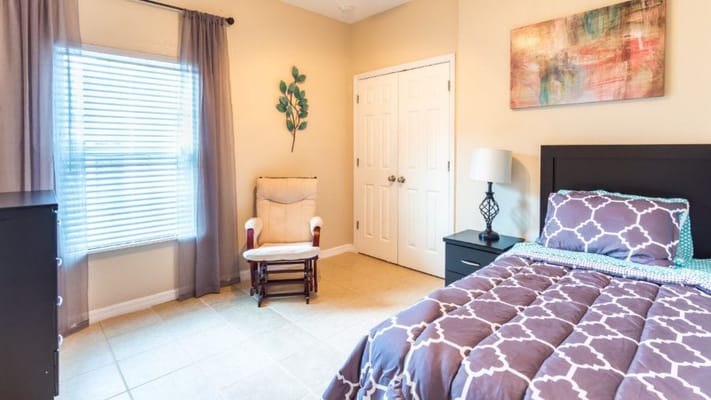 A well-decorated bedroom with a bed, rocking chair, and window.