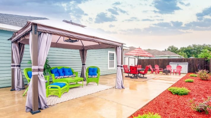 A cozy outdoor lounge area with colorful seating under a gazebo.