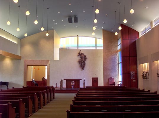 Interior view of the chapel with wooden pews and a religious statue.