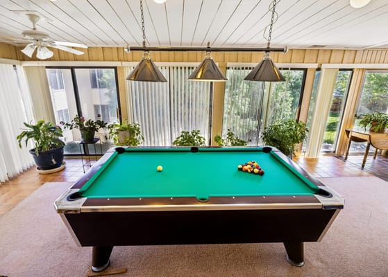 A billiards table with a green felt surface and pool balls arranged on the table.