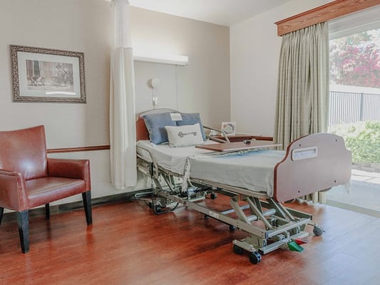 Patient room with an adjustable hospital bed and a brown armchair
