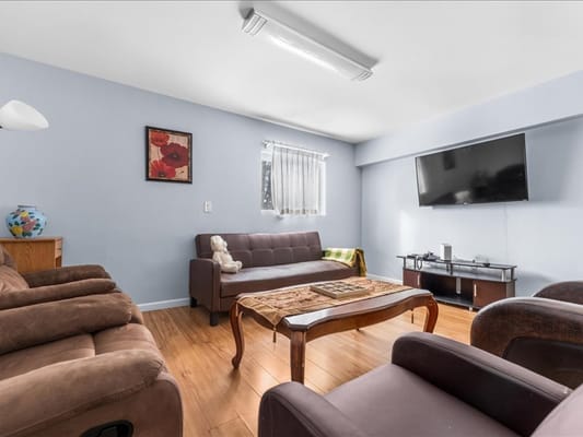 Comfortable lounge with seating and TV in a senior living facility.