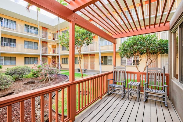 Wooden rocking chairs on a patio in a senior living facility