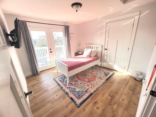 Bright resident room with single bed and colorful rug