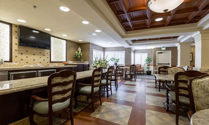 A spacious dining area with wooden chairs and tables, decorated with flowers.