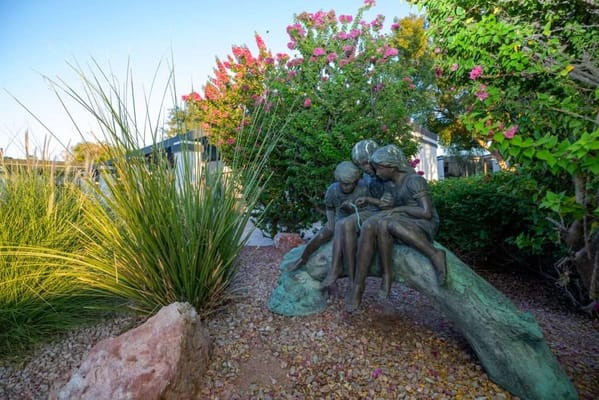 A bronze sculpture of two children in a garden