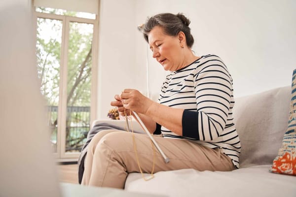 A resident knitting in a cozy living area