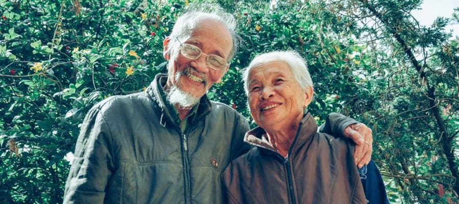 Two seniors smiling together in a garden
