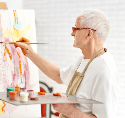 Senior resident painting on an easel in an activity room