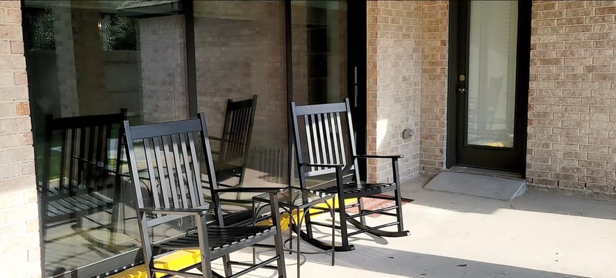 Two black rocking chairs on a porch with a glass door