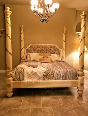 A beautifully decorated bedroom featuring a four-poster bed and chandelier.