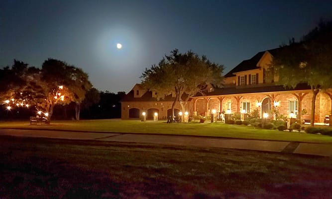 Starwood Manor illuminated at night with a full moon overhead.