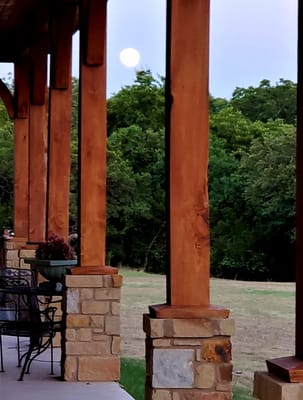 View of the moon from the porch, framed by wooden pillars.
