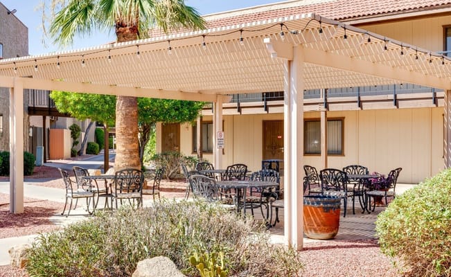 Outdoor seating area with tables and chairs under a pergola