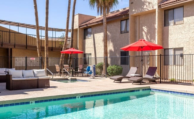 Outdoor pool area with lounge chairs and red umbrellas