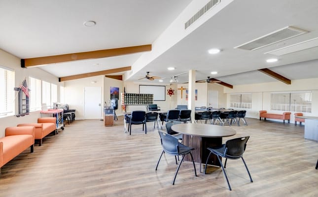 Spacious common area with tables, chairs, and a bulletin board.