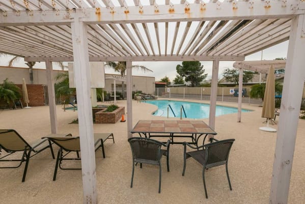 Outdoor pool area with seating and shade.
