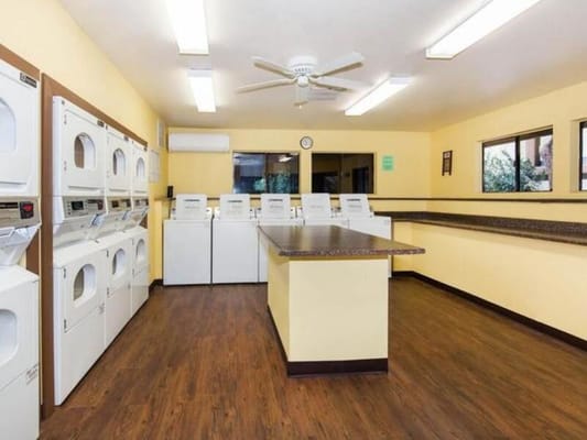 Brightly lit laundry room with multiple washing machines and dryers